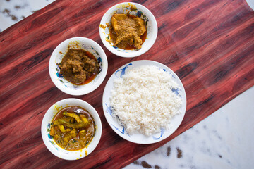 A flavorful spread of Asian dishes, including rice and various curries, arranged on a striking red...