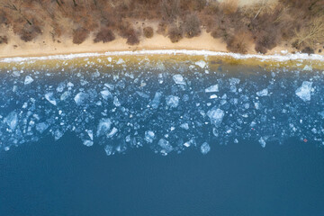 Aerial top down view of a frozen seashore with broken ice.