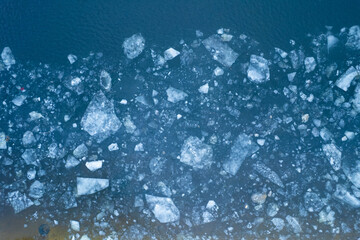 Aerial top down view of a frozen seashore with broken ice.