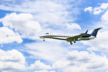 Private business plane flying under blue sky with white clouds