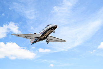 Private business plane flying under blue sky with white clouds