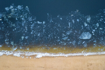 Aerial top down view of a frozen seashore with broken ice.