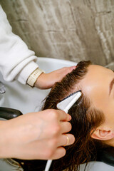 Naklejka premium A close-up of a hairdresser's hand applying a scrub, mask, or color to hair in a salon