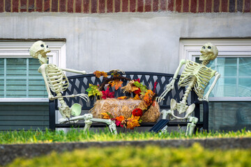 Halloween display with skeletons chatting over hay bale and fall wreath in Boston, Massachusetts,...