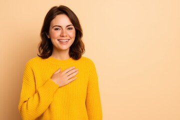 A radiant, sincere woman in a bright yellow sweater smiles warmly at the camera with her hand placed over her heart. This image beautifully conveys trust, gratitude, customer loyalty.