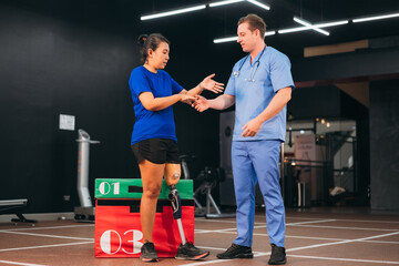 A female patient with a prosthetic leg receiving support from a physiotherapist during rehabilitation exercise, symbolizing recovery, care, and teamwork in modern medical and fitness therapy.