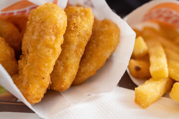 close-up view of crispy fried chicken nuggets and golden french fries served in a paper container.