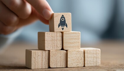 Wooden Blocks With Rocket Graphic In Pyramid Shape: Innovative Start Up Concept With Man Holding Top Block. Launch Your Ideas!