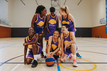 Group of female basketball players celebrating victory in an indoor court