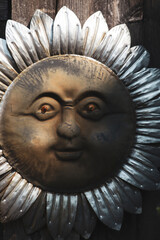 Close-up of rustic metal sun face sculpture with weathered texture. Vintage metallic sun wall art with expressive facial features.