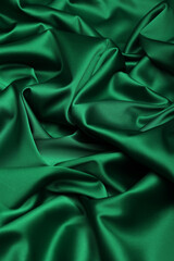 Close-up of luxurious dark green acetate satin fabric, heavily draped and folded to showcase its silky texture, rich luster, and flowing nature, ideal for fashion and elegant apparel design.