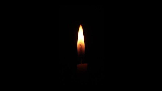 Small candle flame on black background, candle position in the middle of the flame.