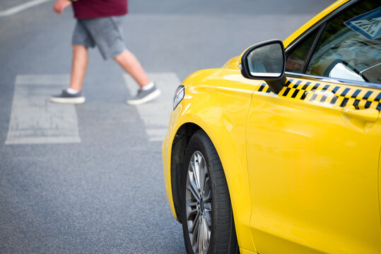 Elderly person crossing road on zebra in front of taxi