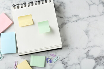 Blank notes and notebook on white marble table, flat lay. Space for text