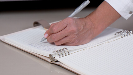 Person writing on a notebook with a pen