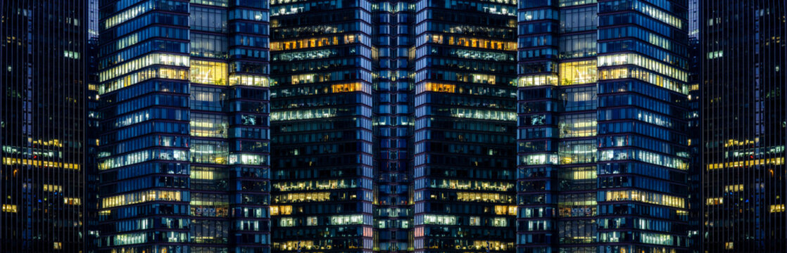 Multi-stories office building at night with worker working overtime. late night at office. lighting and working people within - Powered by Adobe