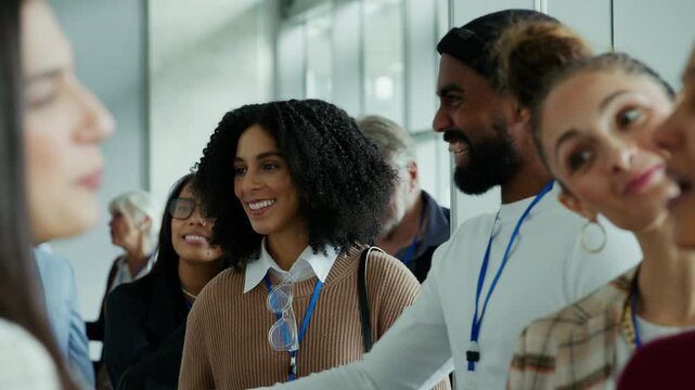 Attendees engage in lively conversation and networking at a busy business conference. People are seen laughing and smiling, sharing ideas, and connecting with colleagues in a social environment.