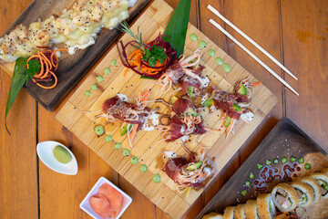 Mesa con muchos platos de sushi y otras comidas asiáticas