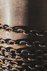 Rusty industrial chains hanging in sunlight. Weathered metal chains on corroded steel surface.
