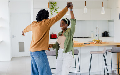 African American couple dancing on tile floor in kitchen around wooden island with red toaster