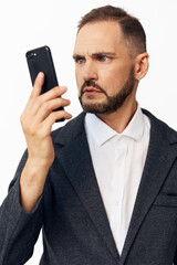 Professional man in a blazer studies a mobile device, conveying focus and determination. Solid...