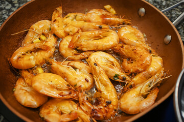 Raw fresh shrimps and langoustines on a frying pan. Close-up of the process of thermal processing of shellfish.