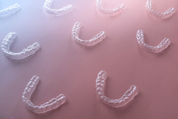 Translucent orthodontic trays on pink-blue gradient, symbolizing invisible smile correction for modern patients. Ideal for dental branding