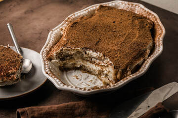 Tiramisu in oval dish on brown background