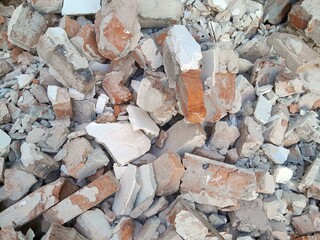 A pile of broken red bricks and fragments of concrete. Pile of debris of a torn down building