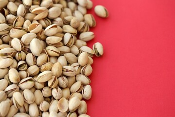 Tasty unpeeled pistachios on bright red background, top view flat lay background pattern