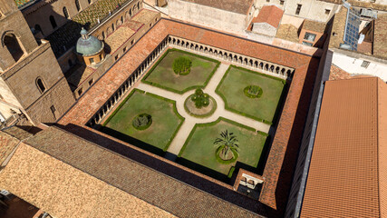 Aerial closeup of the cloister of Monreale Cathedral, located in the province of Palermo, Sicily, Italy. The arched portico and internal garden are empty on this sunny day.
