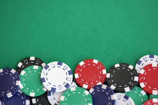 Casino gaming background with stacks of betting chips of different colors on green gaming mat
