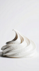 A swirl of white whipped cream on a plain background. The cream has a smooth texture and a glossy finish, ideal for desserts or beverages.