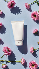 A white cosmetic tube placed on a light blue background surrounded by pink flowers. The scene conveys beauty and skincare themes.