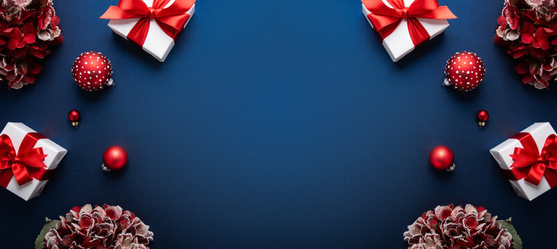 Merry Christmas and Happy Holidays greeting card, frame, banner. New Year. Christmas. Red and white Christmas decorations and gifts on blue background top view. Winter xmas holiday celebration theme. - Powered by Adobe