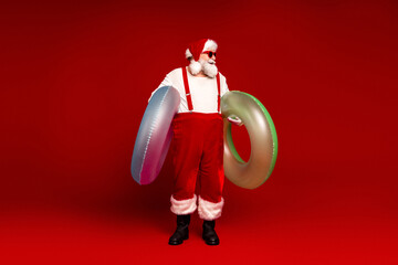 Santa Claus in red suit with inflatable rings posing for holiday fun and family friendly Christmas stock photo