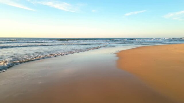 Golden Sands of Serenity: Witness the serene meeting of a sandy shore and the calming expanse of the ocean. Bathed in the warm embrace of sunlight, the scene exudes tranquility. 