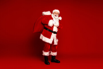 Santa with large red bag greets the season in a red studio backdrop smiling pose for christmas stock image