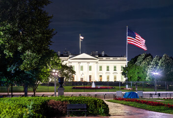 The White House, the official residence of the U.S. President, viewed from Lafayette Square in Washington, D.C. The historic neoclassical building with a United States flag are illuminated at night © Leonid Andronov