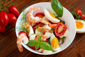 Delicious seafood salad with egg and basil close-up