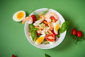 Bowl of fresh salad with seafood flavor and greens on a green background