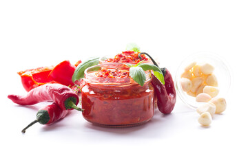 Aromatic red pepper relish in jars with fresh vegetables