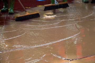 Brushes and boots of workers clean the muddy ground after torrential rains.