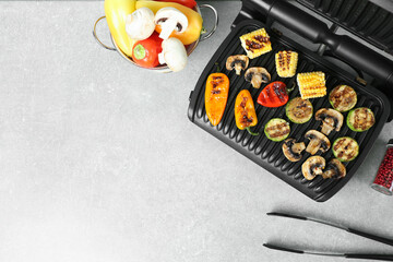 Electric grill with delicious vegetables on light table, flat lay. Space for text
