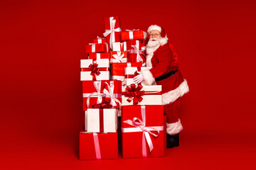 Santa with a tall stack of red and white gift boxes posing for holiday fun in a bright Christmas scene