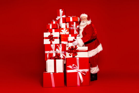 Santa with a tall stack of red and white gift boxes posing for holiday fun in a bright Christmas scene