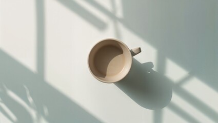 Coffee cup resting on a table with shadows from sunlight