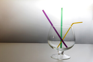 Cocktail straws are in the glass. On a gray background.