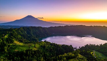 An aerial view showcases a vibrant sunrise illuminating a volcanic mountain and tranquil lake ringed by lush green hills