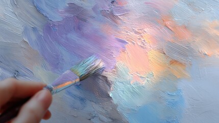 Close-up of a person's hand holding a paintbrush. the brush has a purple handle and white bristles. the background is a textured, abstract painting with a mix of blue, pink, orange, and purple hues.